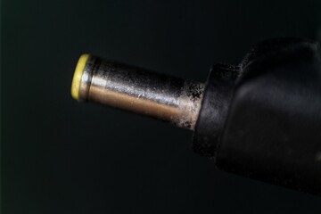 Close-up of a metallic power connector plug, featuring a yellow-tipped pin and textured surface