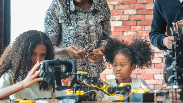 Young Girls Engaged in Robotics and STEM Learning, Diverse Kids Building a Robot Arm in a Science Workshop, Teacher Guiding Girls in Robotics and VR Class