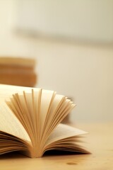 Open book on a wooden table with soft focus background, ideal for education and literary themes,...