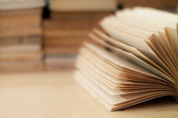 Open book with blurred pages and a background of stacked books, perfect for themes of reading,...