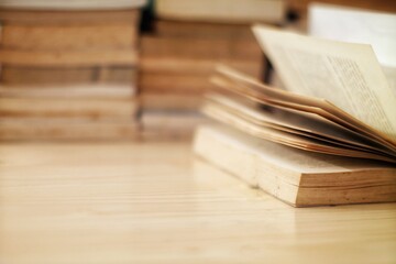 Open book with stacked books in the background, soft focus and warm tones, ideal for education,...