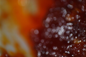 An abstract macro shot featuring blurred red and orange tones with circular bokeh highlights