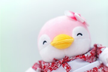 A plush pink penguin toy wearing a floral red dress with a bow and flower hair accessory
