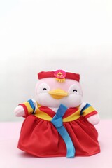 A plush penguin toy dressed in a vibrant red, yellow, and blue traditional Korean hanbok