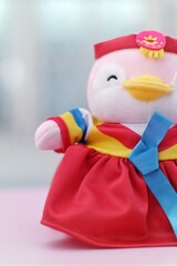 A plush penguin toy dressed in a traditional Korean hanbok with vibrant colors of red, blue, and yellow