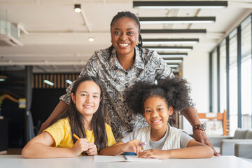 Smiling Teacher with Two Happy Young Students in Classroom, Portrait of a Diverse Group Educator...
