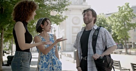 Three friends chat and laugh together in the city. They are enjoying their time together on a summer day.