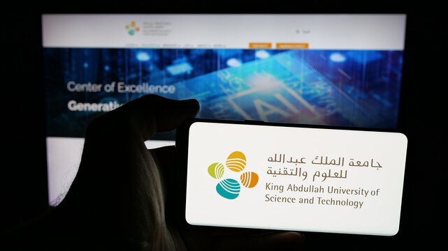 Stuttgart, Germany - 06-14-2025: Person holding mobile phone with logo of Saudi King Abdullah University (KAUST) on screen in front of web page. Focus on phone display.
