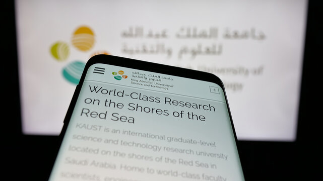 Stuttgart, Germany - 06-14-2025: Mobile phone with website of Saudi King Abdullah University (KAUST) on screen in front of logo. Focus on top-left of phone display.