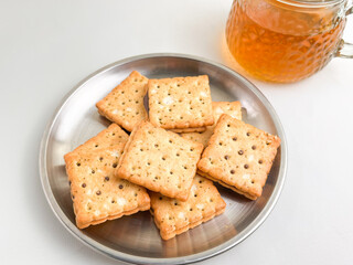 Crispy chocolate biscuits on a stainless steel plate, accompanied by a glass of hot tea