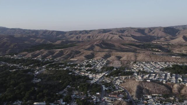 Drone footage at sunrise over Parras de la Fuente, showing urban layout and surrounding terrain under clear sky conditions, captured in stable 4K resolution with smooth tracking and overhead shots.