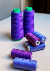 Colorful purple and blue tailoring threads close-up on wooden background.