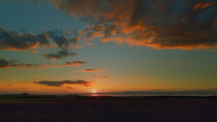 A Stunning Sunset Over Lush Fields Enhanced by Beautiful and Colorful Clouds in the Sky