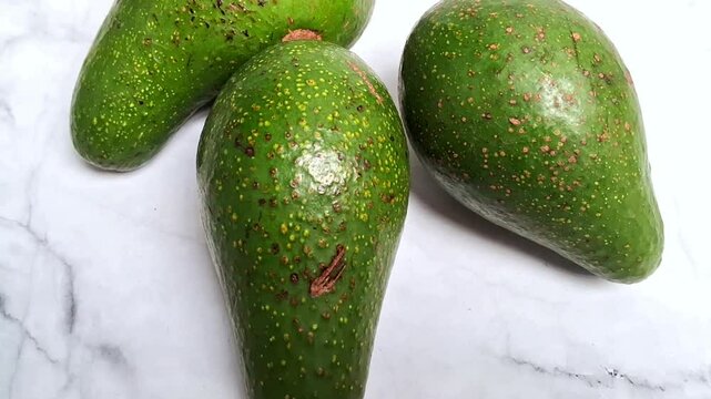 Avocado fruits on white marble background 