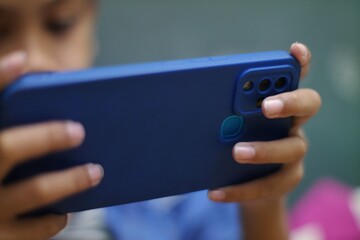 Childs Hands Holding Blue Smartphone Gaming or Watching Video