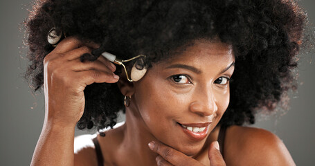 Woman, skincare and jade roller in studio with facial routine, beauty and anti aging by background....