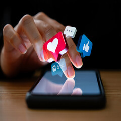 Person using smartphone with social media icons like heart and thumbs up floating