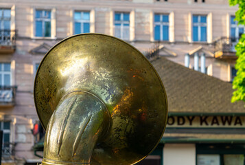 brass tuba during a street music performance, with a historic building and café sign in the...