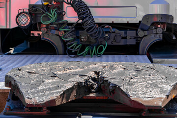 Damaged fifth wheel plate of a semi-truck, showing severe cracks and burn marks. Pneumatic hoses...