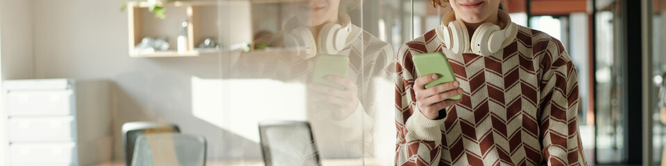 Young adult Caucasian man standing in creative coworking space wearing patterned sweater and...