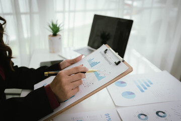 Businessman reviews business infographic on clipboard, analyzing bar and line charts surrounded by...