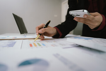 A businesswoman analyzes financial documents with charts and graphs at a desk, highlighting data...