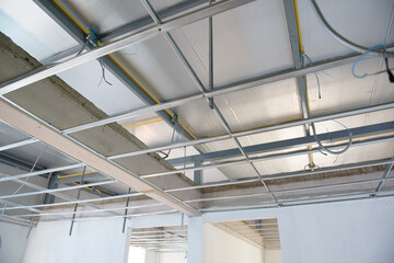 Raw interior renovation showing aluminium ceiling framework. complex electrical wiring installation is visible during construction phase of building project
