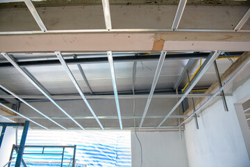 Obraz premium Focused interior renovation shows installation of an aluminium ceiling framework with exposed electrical wiring. complex process is part of home improvement project