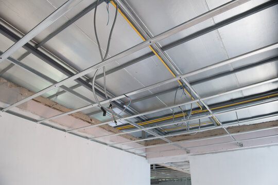 Aluminium ceiling framework with new electrical wiring shows installation progress during an interior renovation project. metal grid structure supports unfinished ceiling