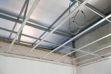 Interior renovation project shows progress with electrical wiring installation within new aluminium ceiling framework. detailed look at building construction and design work
