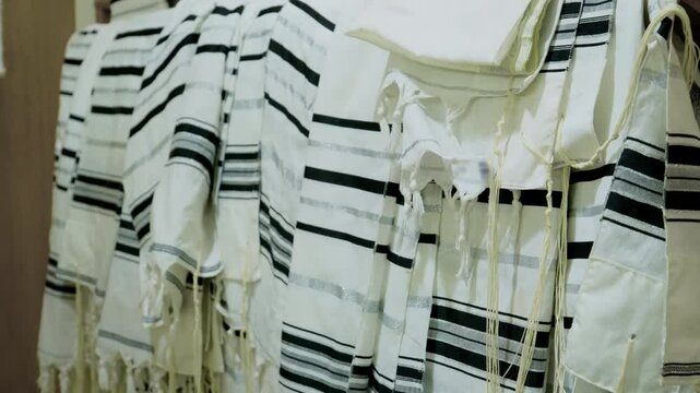 Tallit Jewish prayer shawls hanging neatly, in a synagogue or place of worship. The tallitot with knotted fringes tzitzit.