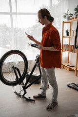 Young long haired man repairing bicycle at home choosing spanner size in bicycle repair tool kit