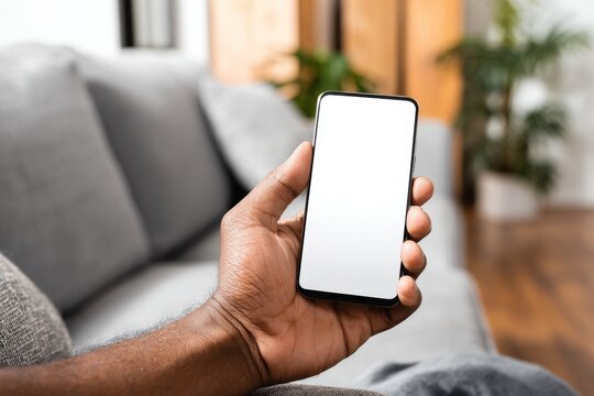 An African American male holds a smartphone, on which the display is a mock white blank screen that is empty and ready for an app