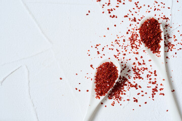 flat lay Korean red chili pepper flake, ground powder coarse paprika or Gochugaru on white table background in spoon with copy space