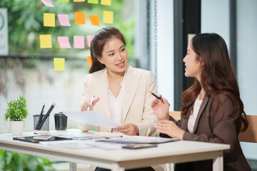 Two Asian businesswomen are sitting in a meeting at the office.