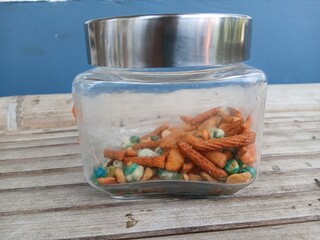 A mix of snacks during Eid such as Bogor peanuts, which taste savory and salty, in a jar on a bamboo chair
