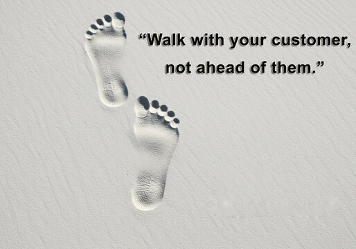 Customer Journey: Step by Step Together -Deep footprints in soft sand beside quote “Walk with your customer” with copy space