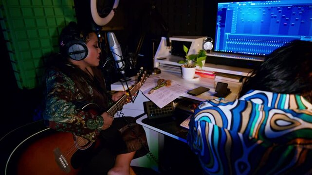 Female Guitarist croons passionately by control board