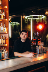 Man Sitting at a Bar Holding a Drink in a Lively Scene