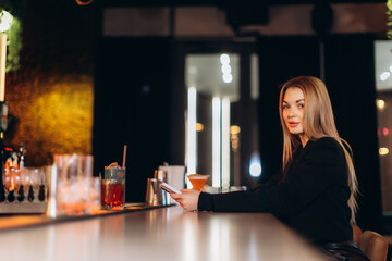 Young Woman Enjoying Drinks at a Trendy Bar Counter