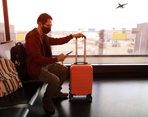 Travel trip with asian young man and backpack as looking the airplane in the hall room with sunlight in the airport terminal