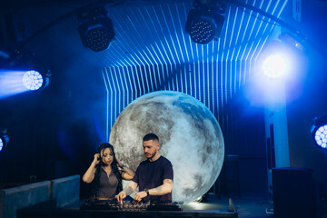 DJs Performing a Music Set Under Unique Lighting with Moon Backdrop