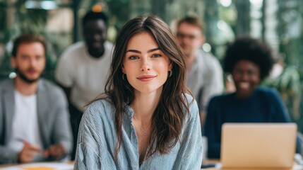 A woman in a pinstripe shirt smiling at the camera with colleagues blurred in the background