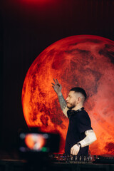 DJ Performing Live with Vibrant Red Planet Backdrop at Night Event