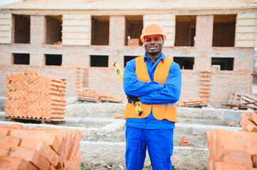 African american construction worker. Portrait of mason bricklayer installing red brick with trowel...