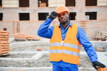 African american construction worker. Portrait of mason bricklayer installing red brick with trowel...