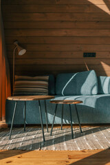 Cozy living room corner with a striped pillow on a blue sofa, two wooden coffee tables, a standing...