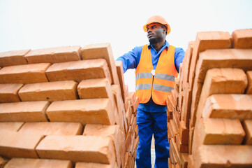 African american construction worker. Portrait of mason bricklayer installing red brick with trowel...