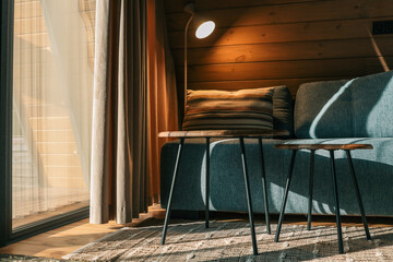 Cozy living room corner with a striped pillow on a blue sofa, two wooden coffee tables, a standing...