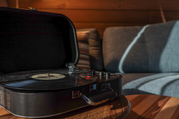 Turntable on a wooden coffee table in a cozy living room with soft lighting, striped pillow on a...